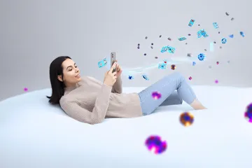 উৎসবের মুহূর্তে ঐতিহ্যবাহী পোশাক পরা এক আনন্দিত নারী তার স্মার্টফোন ব্যবহার করছেন, যা দেখায় KRIKYAA অ্যাপ কীভাবে দৈনন্দিন জীবনের সঙ্গে সহজে মানিয়ে যায়।